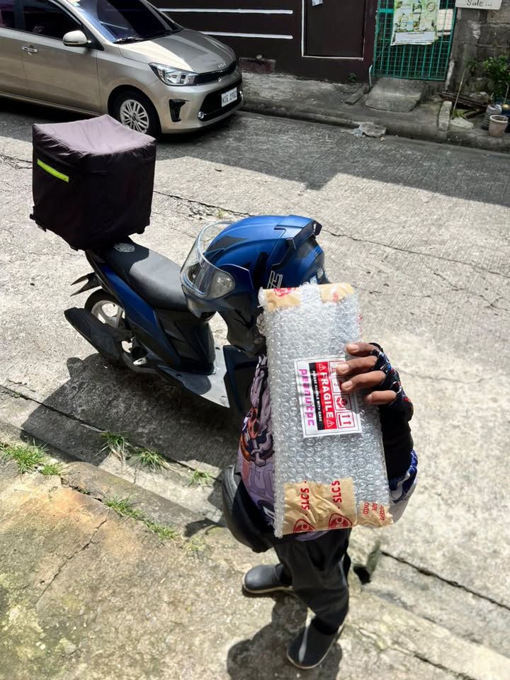 Rider on a scooter carrying a bubble-wrapped parcel